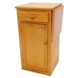 A 20thC pine pedestal cabinet, with single drawer above cupboard on block base, with later drop leaf