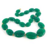 A carved jade necklace, with oval links each engraved with flowers, on yellow metal fine link chain,