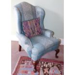 A high wingback upholstered armchair, in George I style, with blue Damask upholstery and carved cabr
