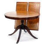 A mahogany extending dining table, the circular top with a brown tool leather insert, on turned colu