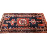 A Persian Hamadan type rug, with a central pole medallion in red on a navy ground with multiple bor