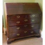 A George III oak bureau, with fall flap revealing a fitted interior, resting on lopers, three short