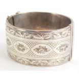 A silver hinged bangle, the front with engraved decoration of leaves and flowers, in three row desig