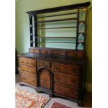 An 18thC oak dresser, with plate rack back having four long spice drawers, the base having central d