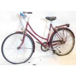 A vintage Raleigh ladies bicycle in purple, with chrome coloured handles and back shelf, 102cm high.