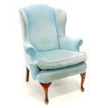 A beech wingback chair, upholstered in blue fabric. The upholstery in this lot does not comply with
