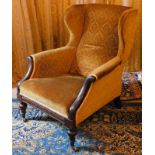 A Victorian mahogany show frame wingback chair, upholstered in gold coloured fabric, on turned legs,