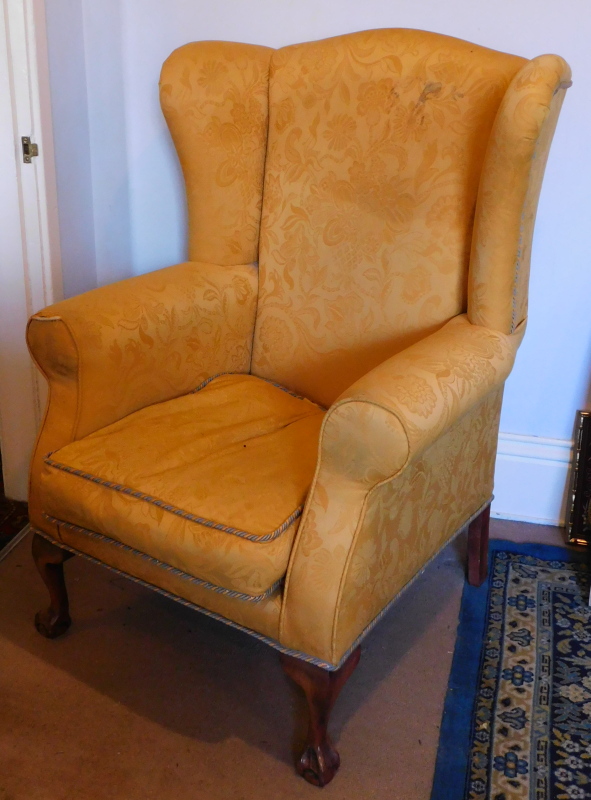 A wingback armchair, with damask upholstery and cabriole legs, with ball and claw feet.