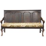 A late 18th/early 19thC oak settle, with a panelled back, shaped arms, and a loose cushion to the ro