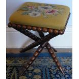 A Victorian bobbin turned stool, with cat-of-nine-tails base, and woolwork floral seat, 38cm square.