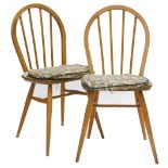 A pair of Ercol stick back kitchen chairs, each with a solid seat on turned tapering legs.
