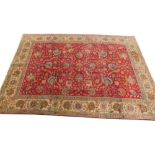 A Persian Tabriz type carpet, with an all over design of flowers, leaves etc., on a red ground with