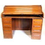 A early 20thC American walnut roll top desk, the tambour front enclosing a fitted interior stamped F