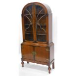 An Art Deco oak display cabinet, with an arched top, two astragal glazed doors enclosing three shape