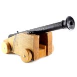 A cast iron replica small canon, on oak trunnion, with solid wheels, the canon 113cm long.