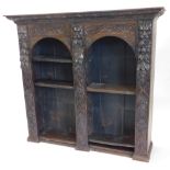 A late 19thC carved oak bookcase, with a shaped cornice above two arched compartments with adjustabl