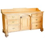 A Victorian stripped pine dresser base, with tray top and three graduated drawers, flanking a centra