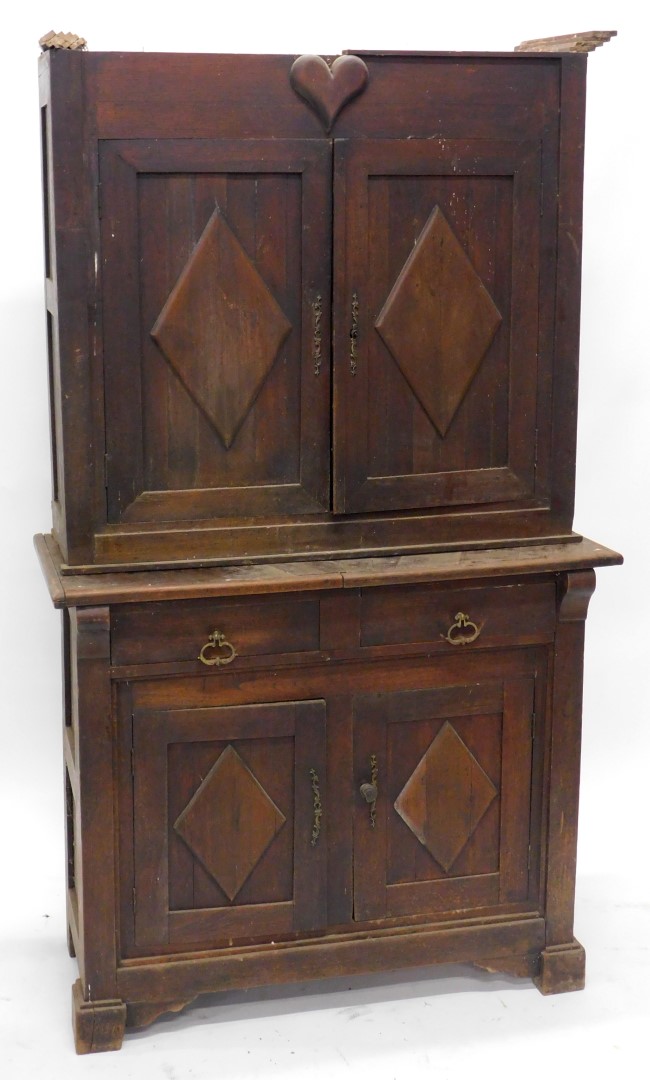 A 19thC French rustic walnut cabinet, the top with a moulded cornice above a heart motif carved to t