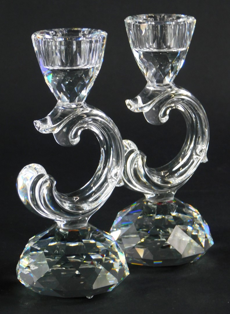 A pair of Swarovski Crystal candlesticks, each with scroll shaped support and faceted tapering base,