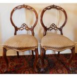 A pair of Victorian walnut cameo back dining chairs, with pierced frames over stuffed seats and cabr