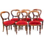 A set of six mahogany balloon back chairs in Victorian style, with a red velvet padded seat on turne