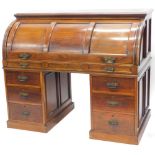 A late Victorian walnut cylinder desk, with a moulded top and a triple panelled fall, enclosing a fi