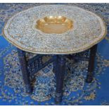 A 19thC Benares brass tray top occasional table, with chip carved hardwood folding base, 78cm diamet