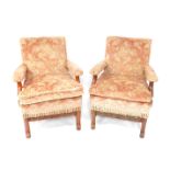 A pair of French early 20thC walnut stained armchairs, each with bolster backs and seats and removab
