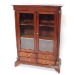 A Regency style mahogany bookcase, the plain top raised above two glazed doors with bevelled glass r
