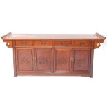 A Chinese style sideboard with scroll top, raised above four drawers with moulded cup handles and qu