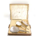 A George V silver backed four piece dressing table set, with engine turned decoration, cased, compri