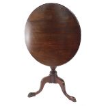A George III mahogany tilt top table, the one piece top on a turned baluster stem terminating in tri