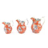 A graduated set of three 19thC transfer printed jugs, each decorated with flowers in black on an ora