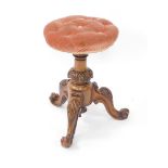 A late Victorian walnut framed piano stool, with overstuffed button adjustable top, on a heavily car