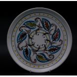 A Denby Glyn Colledge Studio pottery plate, polychrome decorated with leaves in green, yellow and bl