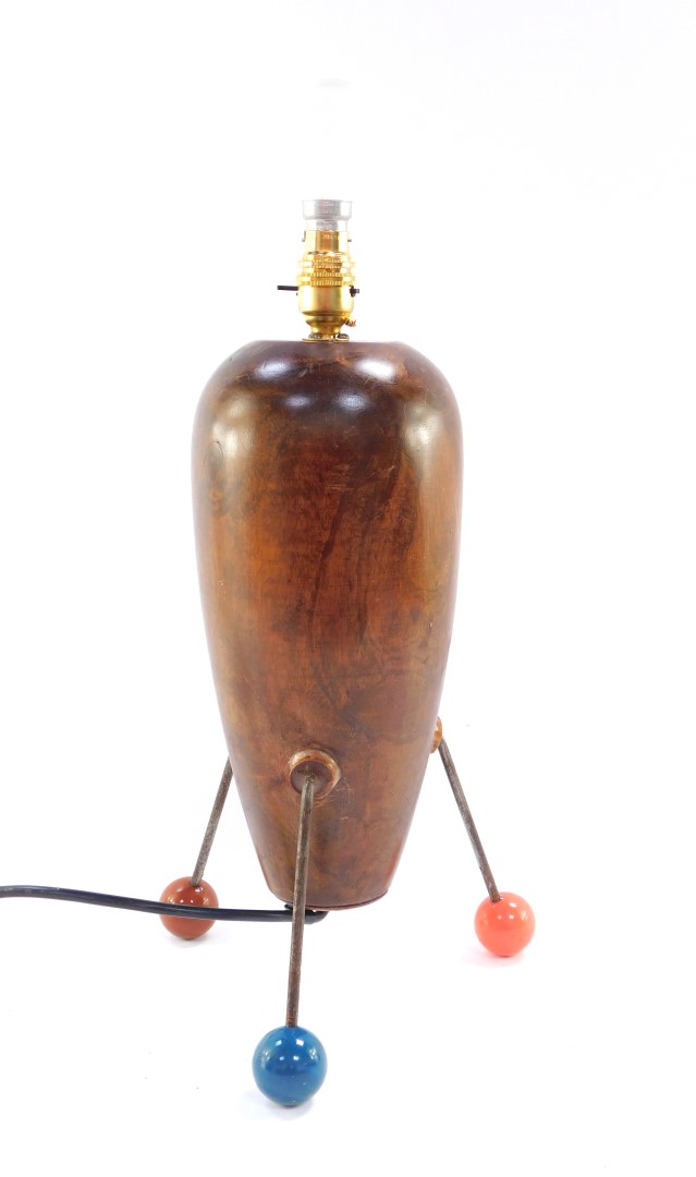 An atomic wooden table lamp, raised on three metal rods and coloured ball feet, 43cm high.