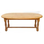 A pine drop leaf wake type kitchen table, raised on turned supports united by an H framed stretcher,