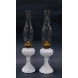 A pair of late 19thC milk glass oil lamps, possibly Sowerby, with moulded fluting and sea serpents,
