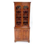 A Georgian style mahogany cupboard bookcase, the dentil moulded pediment over a pair of astragal gla