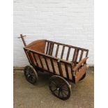 A stained oak four wheel cart, 130cm wide, 69cm deep.