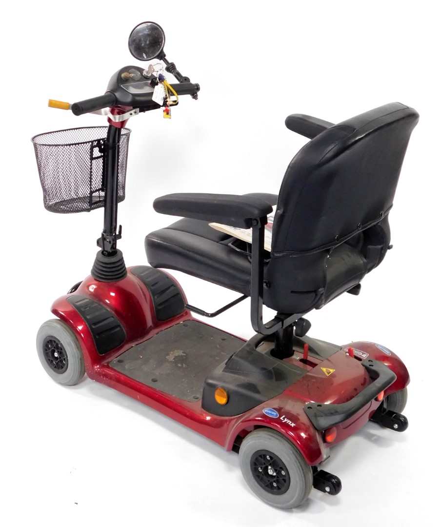 An Invacare Lynx Victory four wheeled mobility scooter, in red and black colourway, with front baske