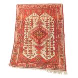 A 20thC Iranian rug, the bold central medallion and outer floral and geometric field, in red, cream