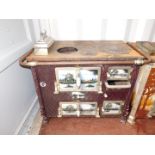 A Continental early 20thC cast iron and enamel kitchen range, the doors and sides decorated with pan