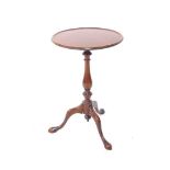 A George III style mahogany tripod table, the moulded circular top raised on a baluster stem termina