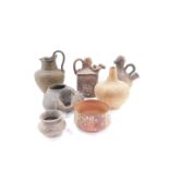 A group of world replica brown glaze pottery, including a Greek jug carved with bands of animals, a