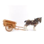 A Melrose pottery shire horse, brown gloss, 37cm wide., together with a wooden cart, 44cm wide. (2)