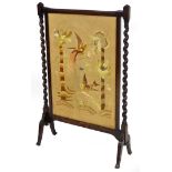 A late 19thC oak framed fire screen, the rectangular centre raised and embroidered with exotic birds