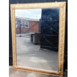 A large rectangular gilt framed wall mirror, the corners with flowers, leaves and vines, 143cm x 110