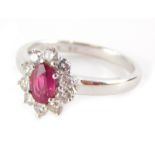 An 18ct gold ruby and diamond cluster ring, the oval cut ruby totalling 0.50cts overall, surrounded