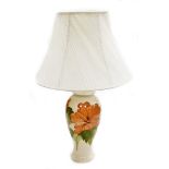 A Moorcroft table lamp, coral hibiscus pattern, in cream decoration with flowers and leaves with a c
